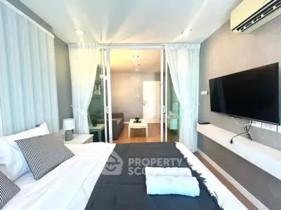 Modern bedroom with stylish decor, featuring a wall-mounted TV and sliding glass doors leading to a cozy living area.