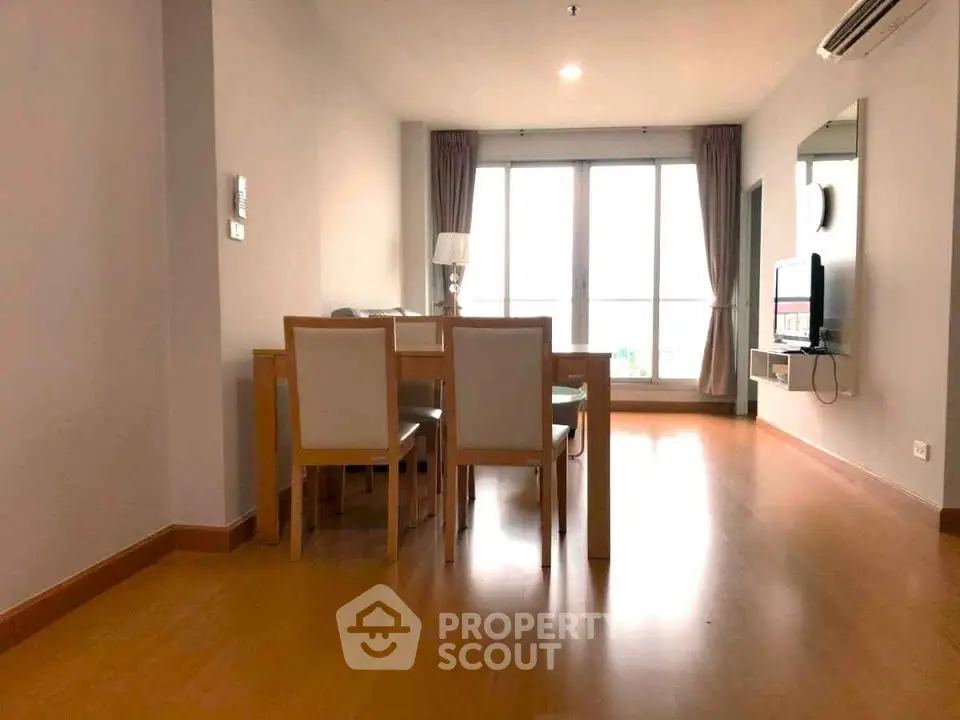 Spacious living room with modern dining set and large windows for natural light.