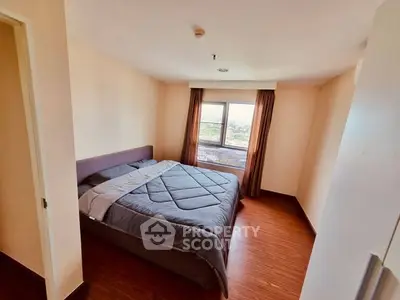 Cozy bedroom with large window offering a stunning city view, featuring a comfortable bed and elegant wooden flooring.