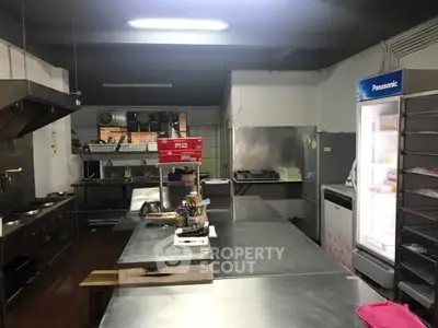 Spacious commercial kitchen with stainless steel counters and modern appliances.