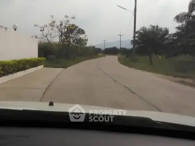 Scenic driveway leading to a serene residential area with lush greenery.
