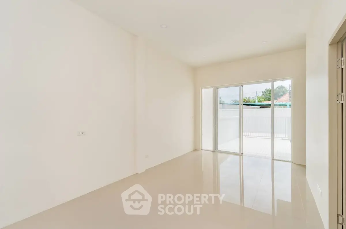 Spacious empty room with sliding glass doors leading to a bright balcony, perfect for customization.