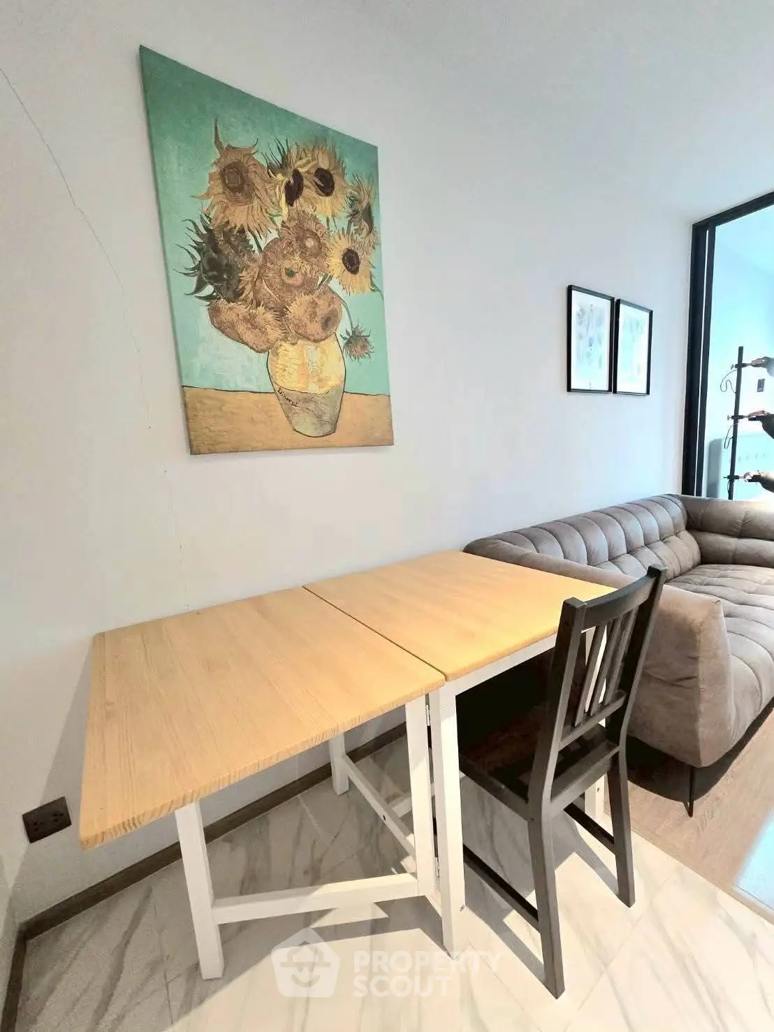 Modern living room with stylish sofa and sunflower artwork, featuring a cozy dining area.