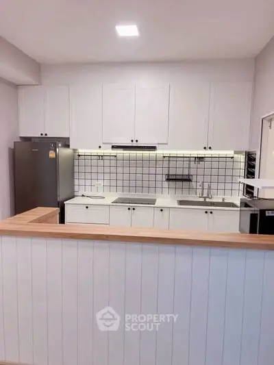 Modern kitchen with sleek white cabinets and tiled backsplash in open layout design.