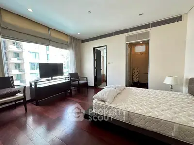 Spacious bedroom with modern furnishings and large window view.