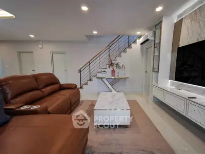 Modern living room with leather sofas and stylish staircase