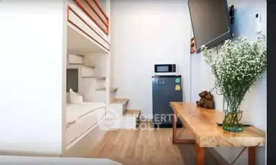 Modern compact living space with loft bed, fridge, and TV