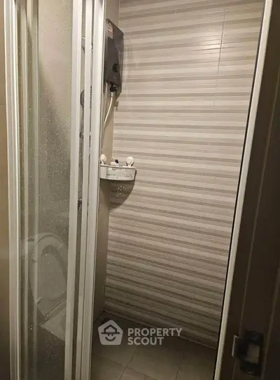 Compact bathroom with shower enclosure and modern striped tiles