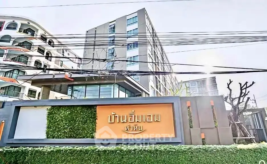 Modern apartment building exterior with lush greenery and stylish signage.