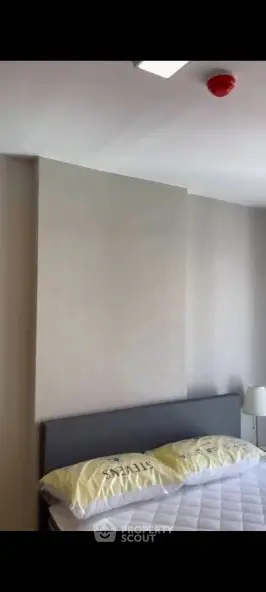 Modern bedroom with minimalist design and neutral tones, featuring a comfortable bed and stylish lighting.