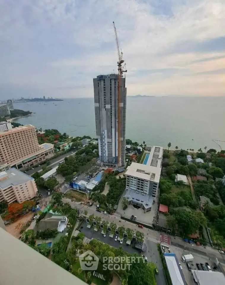 Stunning aerial view of high-rise building under construction near the ocean, showcasing prime real estate location.