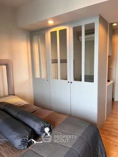 Modern bedroom with stylish wardrobe and cozy bedding in a well-lit space.