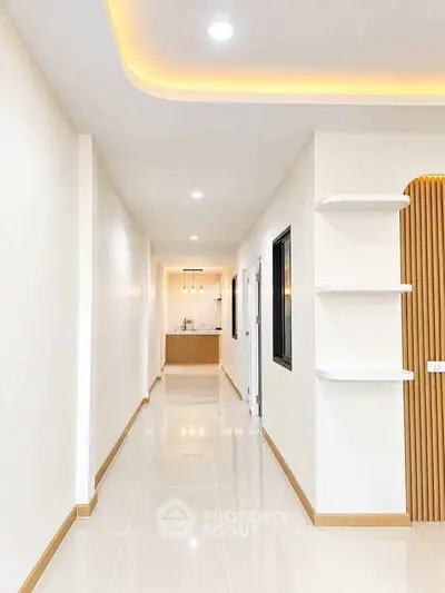 Modern hallway with sleek design and recessed lighting leading to a stylish kitchen.