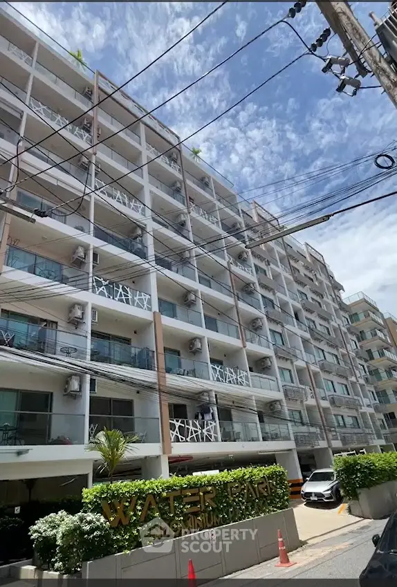 Modern condominium building with lush greenery and clear blue sky