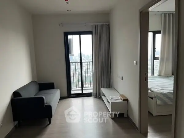 Modern apartment interior with living room and bedroom, featuring sleek furniture and city view balcony.