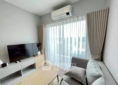 Modern living room with sleek furniture and large window offering natural light.