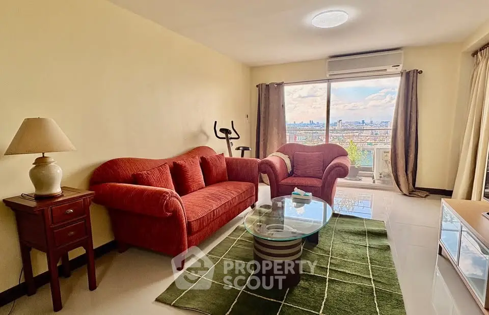 Spacious living room with city view, featuring cozy red sofa set and modern decor.