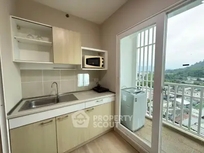 Modern kitchen with balcony view, featuring sleek cabinetry and appliances in a high-rise apartment.