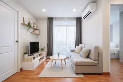 Modern living room with cozy sofa, TV, and natural light from large window.