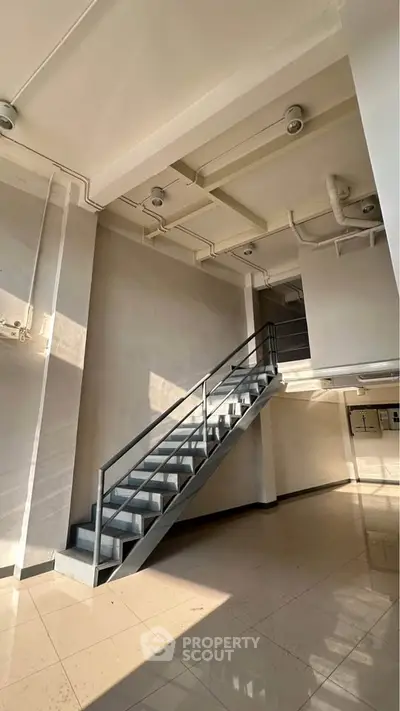 Spacious industrial-style interior with metal staircase and high ceiling