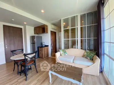 Charming living room with cozy sofa and dining area, featuring wooden flooring and natural light.