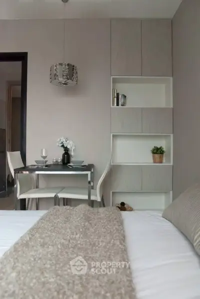 Cozy bedroom with modern dining area and built-in shelving, perfect for urban living.