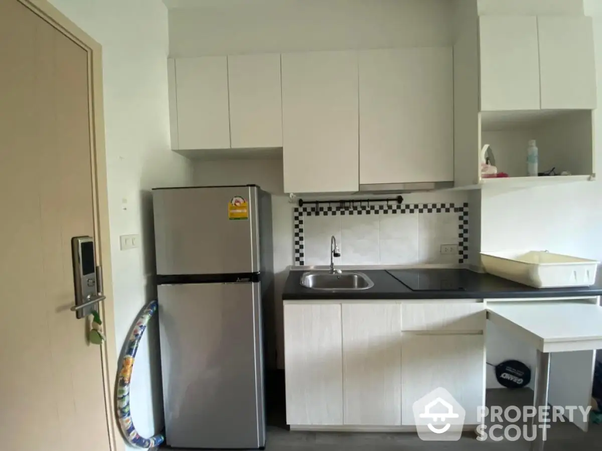 Modern compact kitchen with sleek cabinetry and stainless steel fridge