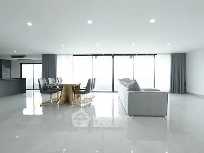 Spacious modern living room with elegant dining area and large windows offering abundant natural light.