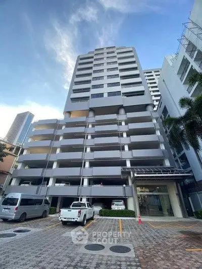 Modern high-rise building with parking area and clear blue sky