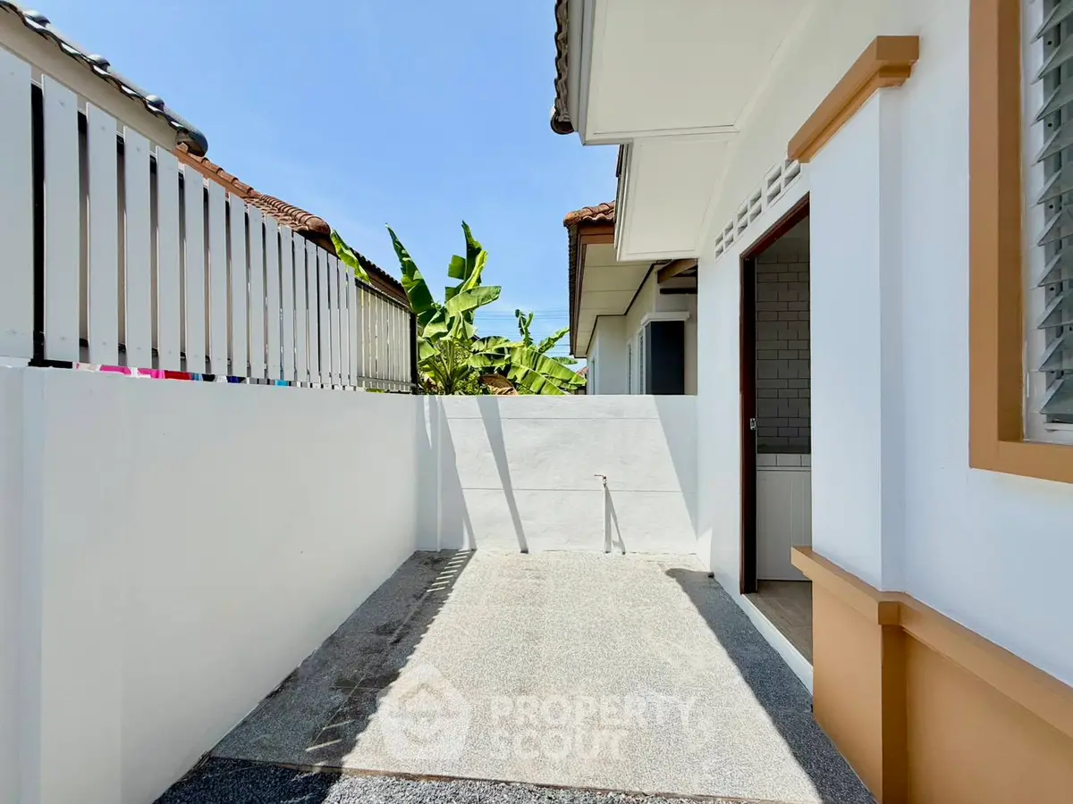 Charming exterior view of a modern home with a small outdoor space and lush greenery.