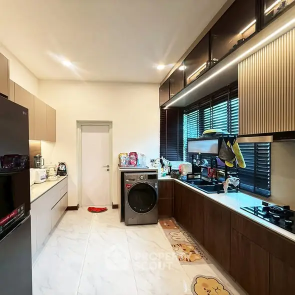 Modern kitchen with sleek cabinets and built-in appliances, featuring a washing machine and gas stove.