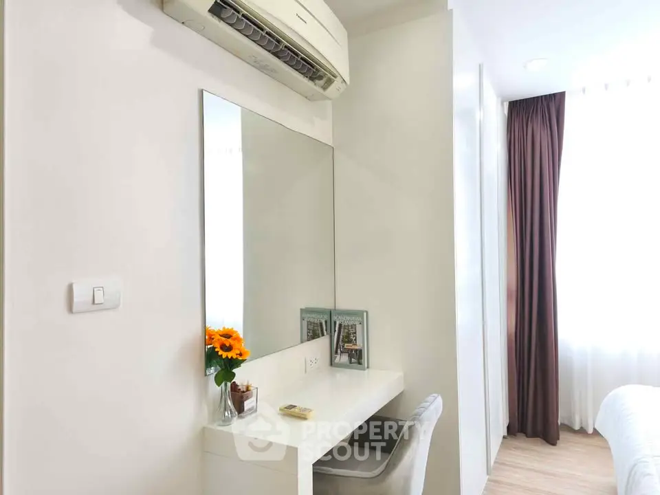 Modern bedroom with sleek white vanity and air conditioning, featuring natural light and elegant decor.