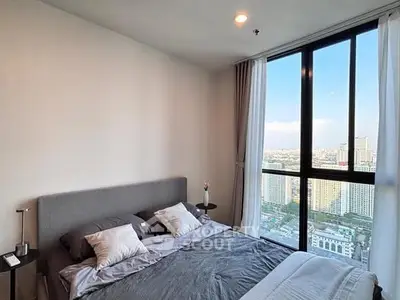 Modern bedroom with large window offering stunning city view, featuring a cozy bed and elegant decor.