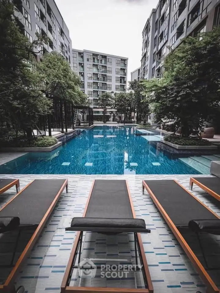 Luxurious apartment complex with a stunning outdoor pool and modern lounge chairs.