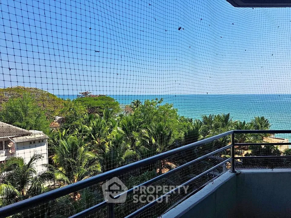 Stunning ocean view from a balcony with lush greenery and clear blue skies.