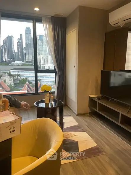 Modern living room with city view, featuring stylish furniture and large window.