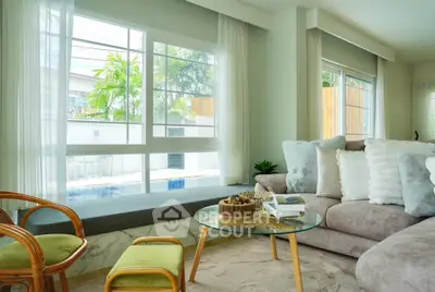 Bright and cozy living room with large windows and pool view, featuring plush sofa and stylish decor.