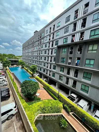 Modern apartment building with pool and parking, lush greenery, and spacious design.