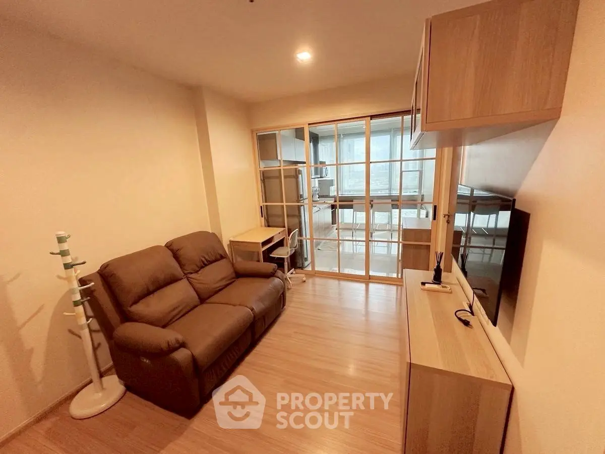 Cozy living room with modern furniture and sliding glass doors leading to a bright balcony.