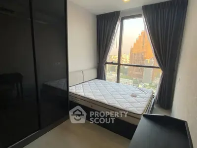 Modern bedroom with large window and city view, featuring sleek black furniture and cozy ambiance.