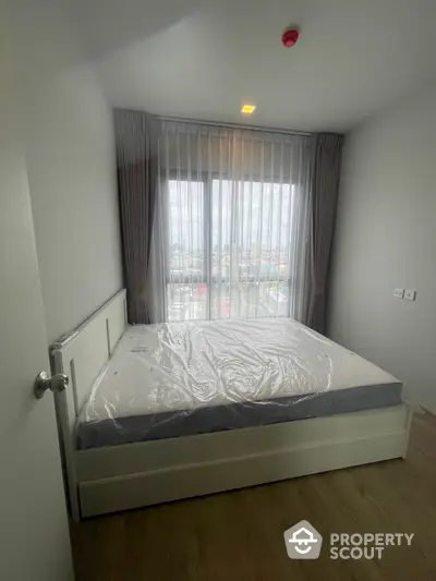 Cozy bedroom with large window and natural light in modern apartment.