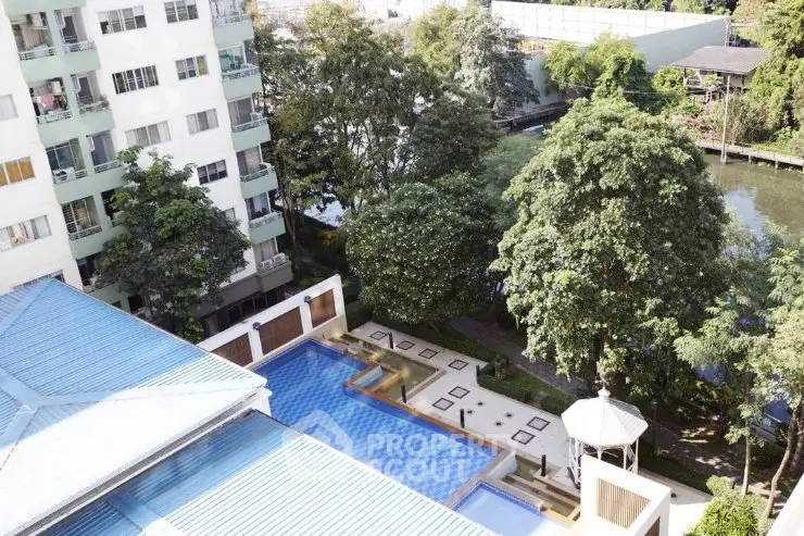 Stunning aerial view of a modern apartment complex with a luxurious pool and lush greenery.