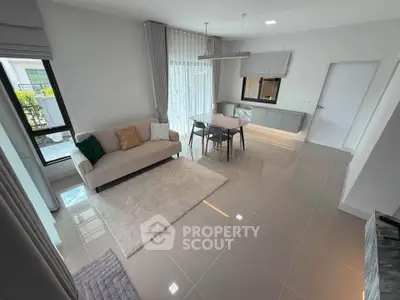 Modern living room with elegant dining area and large windows for natural light.