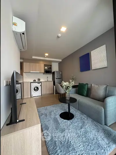 Modern living room with open kitchen, featuring stylish decor and appliances, perfect for urban living.