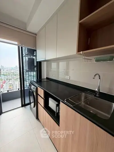 Modern kitchen with sleek cabinetry and city view from balcony, featuring built-in appliances and ample counter space.