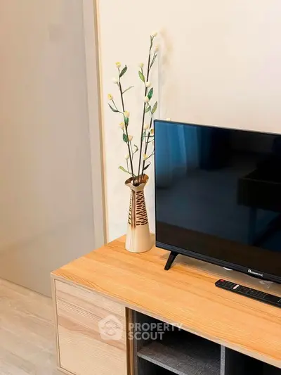 Modern living room with stylish TV stand and decorative vase, perfect for cozy entertainment setup.