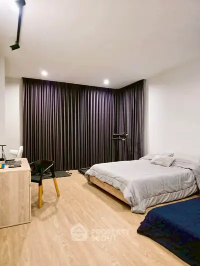 Spacious modern bedroom with stylish decor and wooden flooring