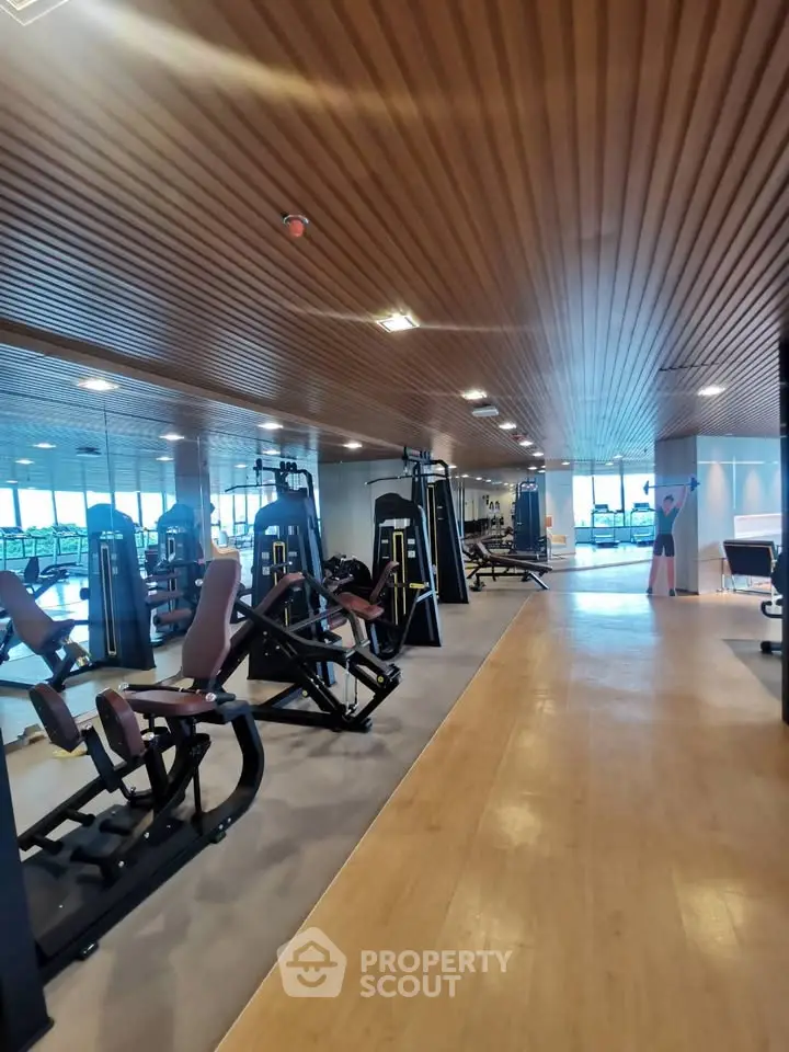 Spacious modern gym with state-of-the-art equipment and wooden ceiling design.