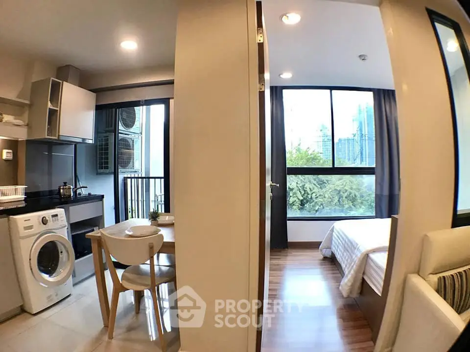 Modern apartment interior with kitchen, dining area, and bedroom featuring large windows and natural light.