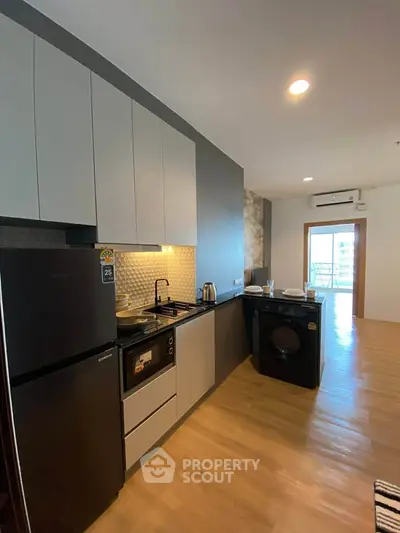 Modern kitchen with sleek cabinets, built-in oven, and washing machine in a stylish apartment.